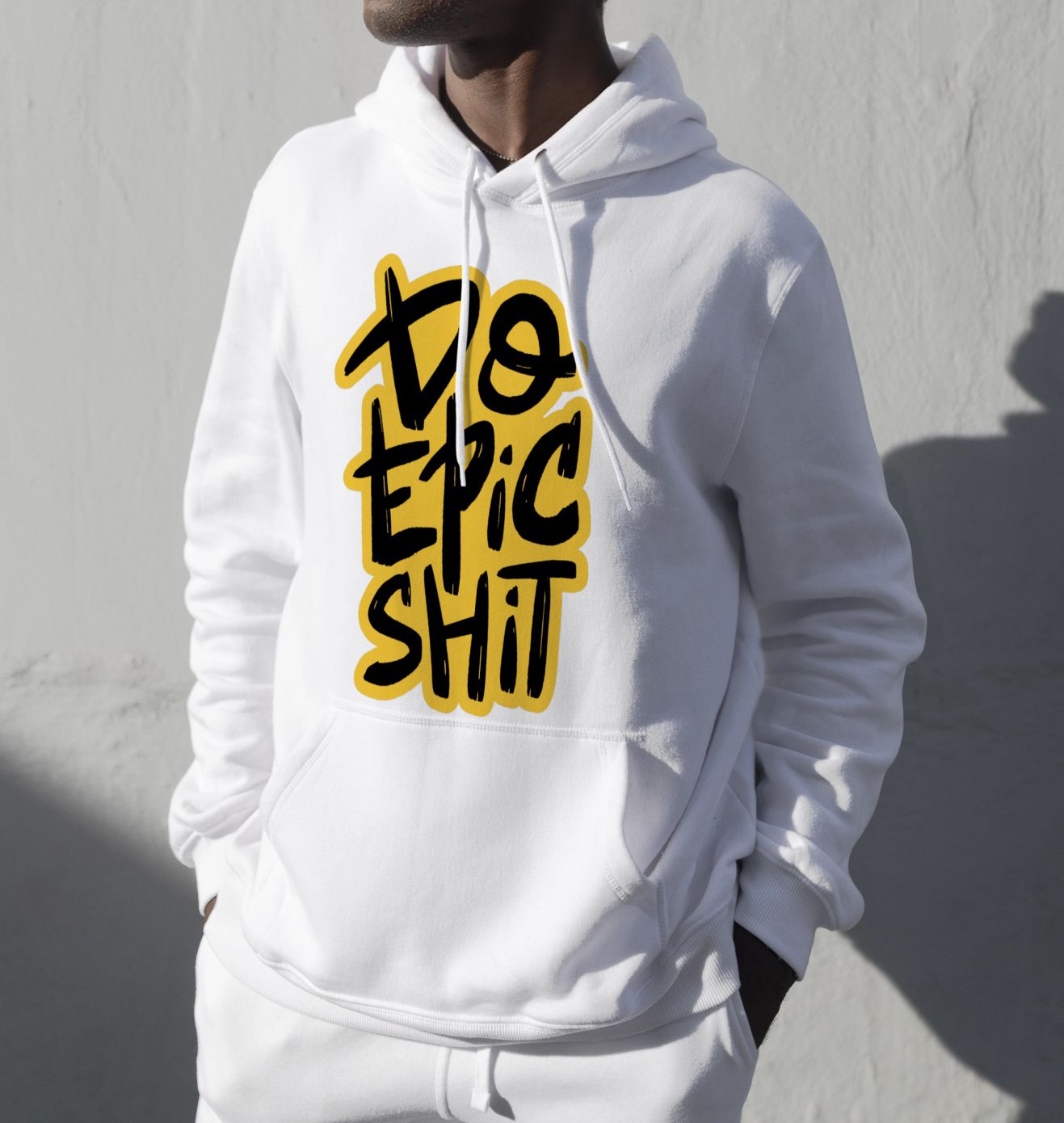 Person, die einen weißen Kapuzenpullover mit einem fettgedruckten gelben und schwarzen Text trägt, auf dem steht: „Do Epic Shit.“.