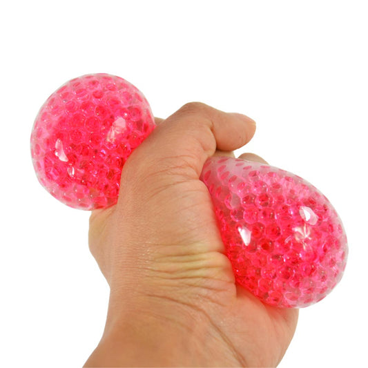 Eine Hand drückt den 7 cm großen Crystal Beads Ball von www.buyon.at, der mit leuchtend pinken Wasserperlen gefüllt ist. Der Stressball dehnt sich unter Druck aus, wodurch die Perlen besser sichtbar werden und als effektives Stressabbau-Tool dienen.