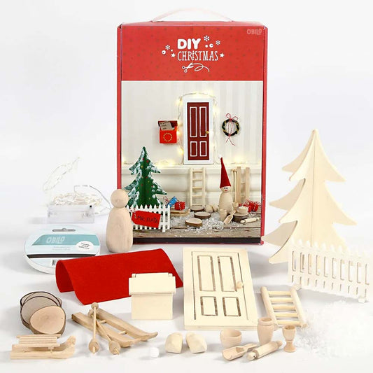 Ausgestellt wird das DIY Wichteltür-Set Deluxe XL von www.buyon.at, bestehend aus kleinen Holzfiguren, einem Miniaturbaum, einer Leiter, einem Zaun, einer Wichteltür, kleinen Dekorationen und diversen Bastelmaterialien. Die Hintergrundbox zeigt eine festliche Weihnachtsszene mit dem Aufdruck „DIY Christmas“ – perfekt für die Vorweihnachtszeit.