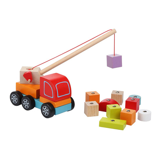 Der Holzspielzeug Kranwagen mit Magnet von www.buyon.at hat eine rote Karosserie und blaue Räder und einen langen Arm mit einer roten Schnur und einem magnetischen Haken, der einen violetten Block anhebt. Dieser charmante Holzspielzeug-Kranwagen ist von bunten Blöcken in Gelb, Grün, Weiß, Rot und Beige umgeben.