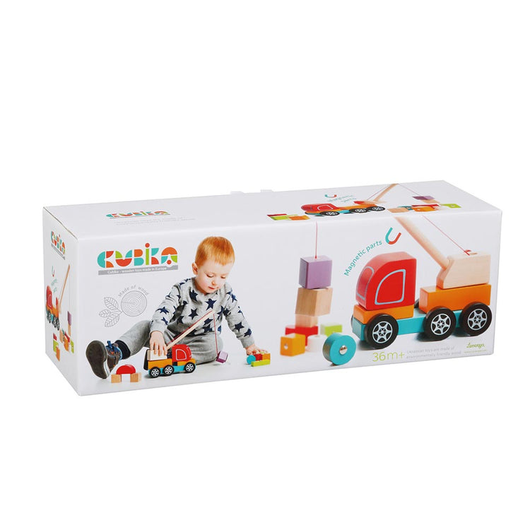 Eine Spielzeugschachtel mit einem Kind, das mit bunten Lernbausteinen, einem Spielzeuglastwagen und dem Holzspielzeug Kranwagen mit Magnet spielt. Auf der Schachtel sind der Markenname „www.buyon.at“, Abbildungen der enthaltenen Spielzeuge und die Erwähnungen „magnetische Teile“ und „36m+“ zu sehen. Der Hintergrund ist weiß.