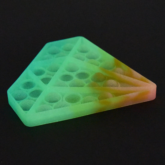 Das Fidget Plopp Up, Glow in Dark Diamant von www.buyon.at ist ein mehrfarbiges, weiches Silikon-Pop-it-Spielzeug in Form eines Diamanten. Das Spielzeug verfügt über ein Farbverlaufsmuster in Grün-, Gelb- und Orangetönen und mehrere blasenartige Tasten zum Drücken. Es leuchtet sogar im Dunkeln, wobei ein schwarzer Hintergrund seine leuchtenden Farben hervorhebt.