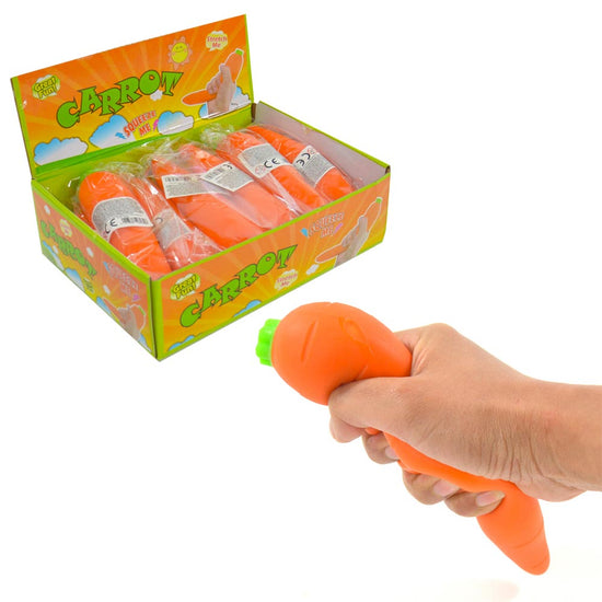 Im Vordergrund eine Hand, die ein Quetschkarotte-Spielzeug aus Gummi drückt. Im Hintergrund sind mehrere dieser www.buyon.at Kinderspielzeuge in einer offenen Schachtel vor einer bunten Verpackung mit der Aufschrift „Carrot Super Squeeze“ zu sehen. Perfekt für Stressabbau und stundenlangen Spielspaß!