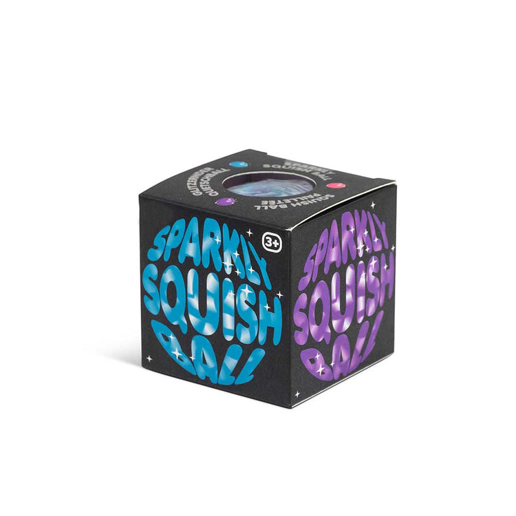 Eine schwarze würfelförmige Box von www.buyon.at mit einem bunten, glänzenden Design und dem Schriftzug „Sparkly Squish Ball“ in Blau und Lila, geeignet für Kinder ab 3 Jahren. Die Verpackung zeigt holografischen Text und kleine mehrfarbige Symbole, die darauf hinweisen, dass es sich um ein Spielzeug mit beruhigender Wirkung handelt.