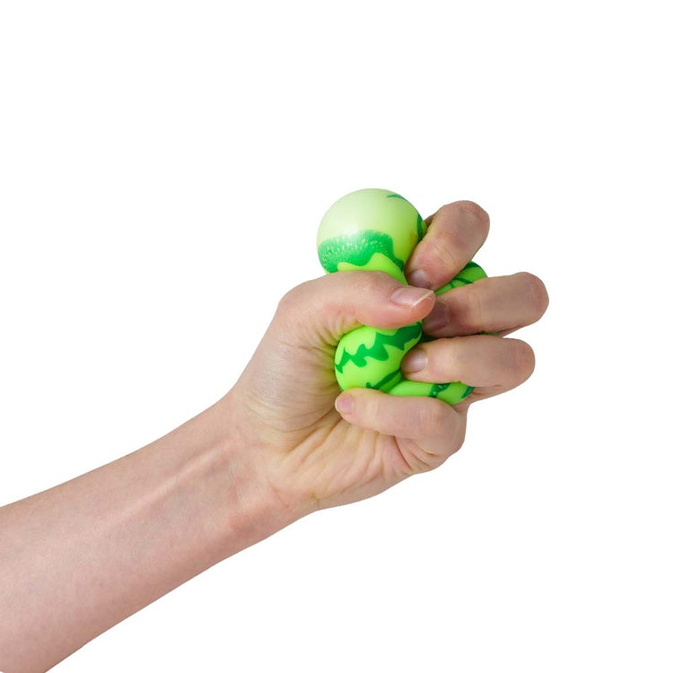 Eine Hand drückt einen Stretchy Wassermelone Stressball mit Zickzack-Muster auf weißem Hintergrund, erhältlich bei www.buyon.at.