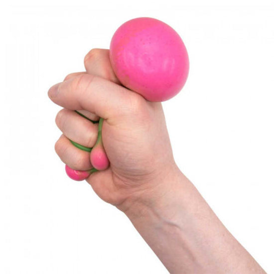 Eine Hand drückt eine rosa Stretchy Wassermelone von www.buyon.at, die sich zwischen den Fingern leicht wölbt. Der Hintergrund ist weiß.