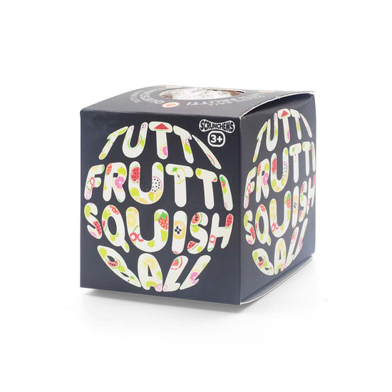 Eine schwarze Würfelbox von www.buyon.at mit der Aufschrift „Tutti Frutti Squish Ball“, gestaltet mit farbenfrohem Obst-Schriftzug. Die Verpackung, geeignet für Kinder ab 3 Jahren, zeigt verspielte und lebendige Obst-Illustrationen, die Stressabbau und Entspannung fördern.