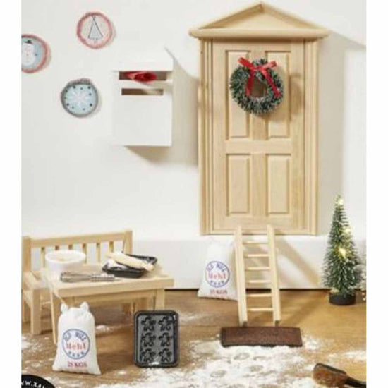 Die Miniaturküchenszene von www.buyon.at zeigt die Wichteltüre „Weihnachtsbäckerei“, komplett mit einem kleinen Holztisch und einer Bank, Backutensilien, einem winzigen Weihnachtsbaum, einer Tür mit der Wichteltüre, einer Leiter und einem Minibriefkasten. Verstreute Mehlsäcke und ein Keksblech verleihen der Weihnachtsbäckerei den festlichen und gemütlichen Charme.